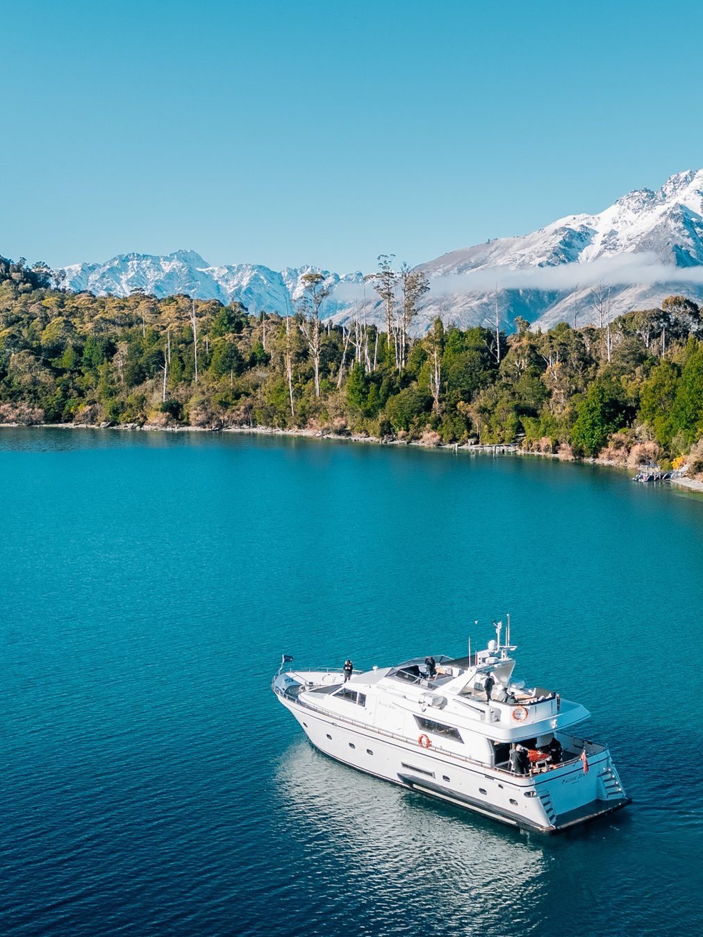 Pacific Jemm anchored in a sheltered bay on Lake Wakatipu beneath snow-capped peaks
